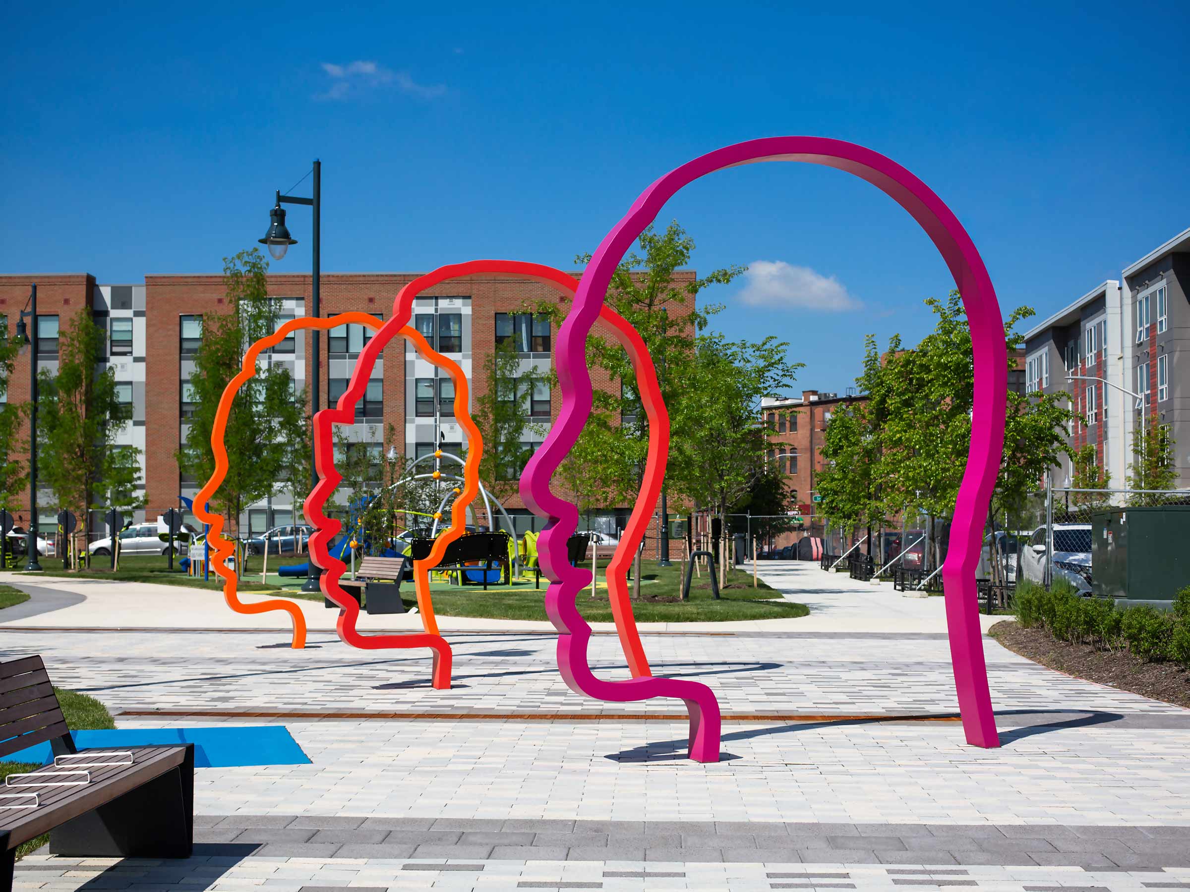 Harmonic Time public art installation is a new contemporary monument composed of a colonnade of three colorful monumental 12-foot-tall silhouette portraits in a gradient of orange, red, and purple.