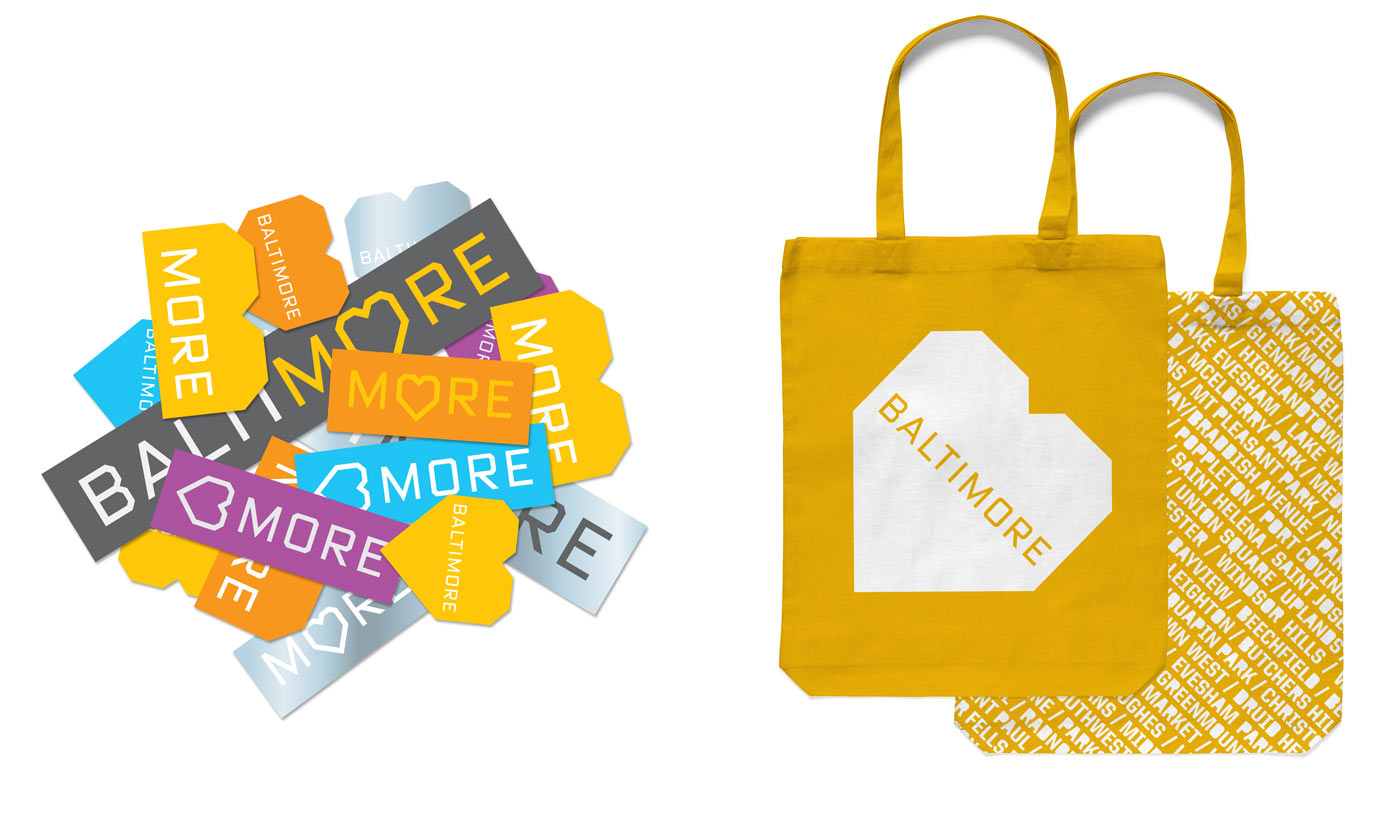 A tilted B/heart shape used as proposed branding for the city of Baltimore, shown on stickers and tote bags