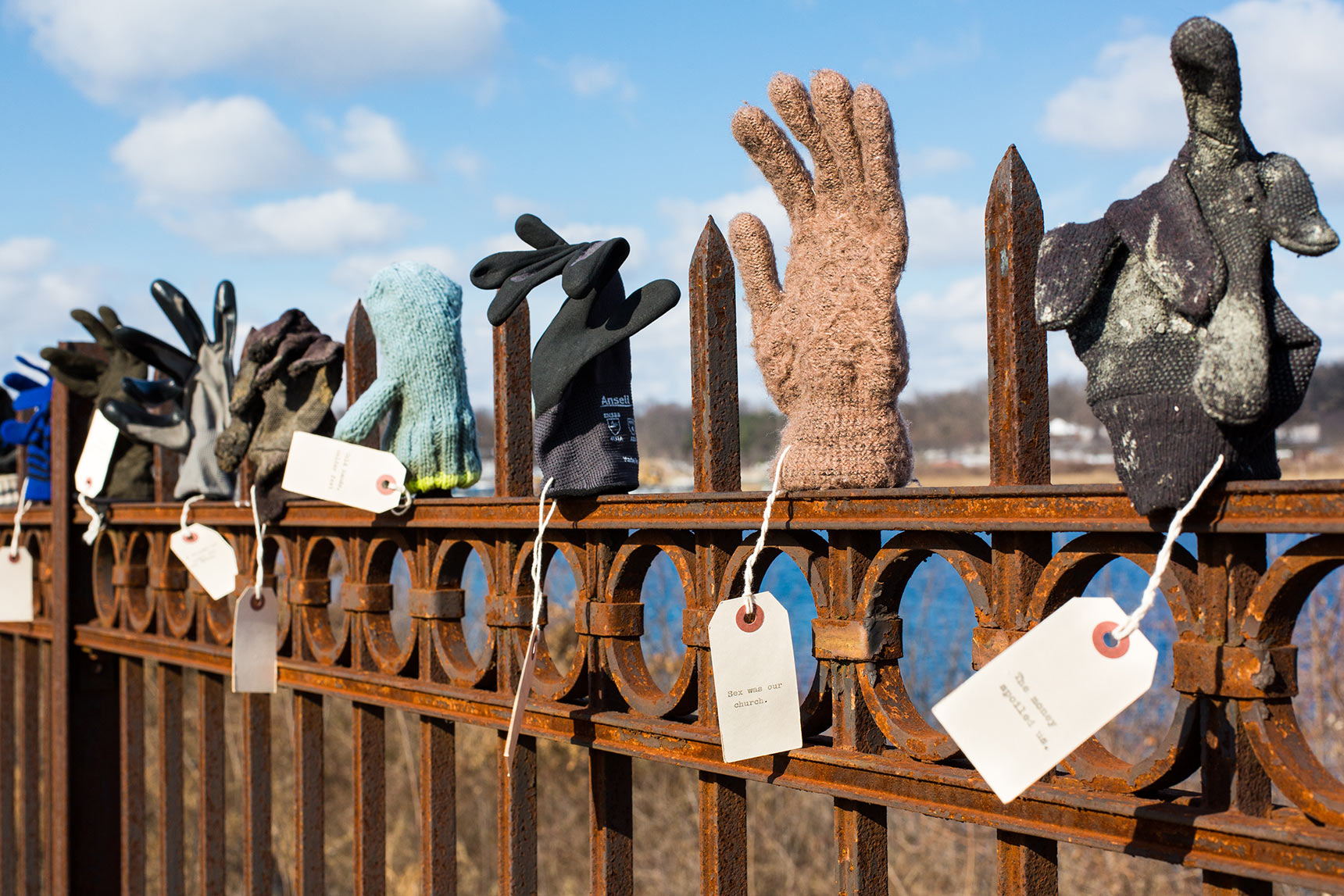 Dozens of found orphaned gloves and mittens displayed on a wrought iron fence in the Library of Lost Gloves & Lost Loves participatory public art installation by artist Bruce Willen