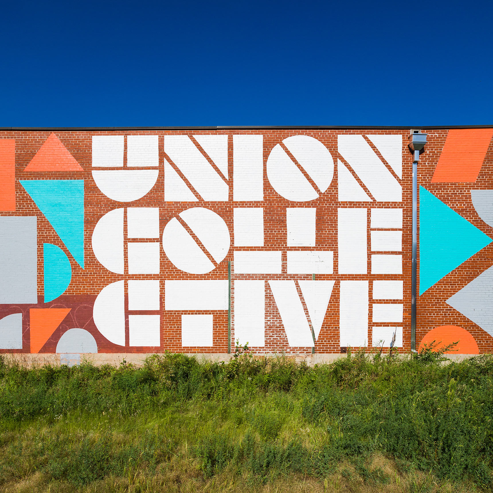 Union Collective geometric stencil logo mural on the side of a warehouse building in baltimore