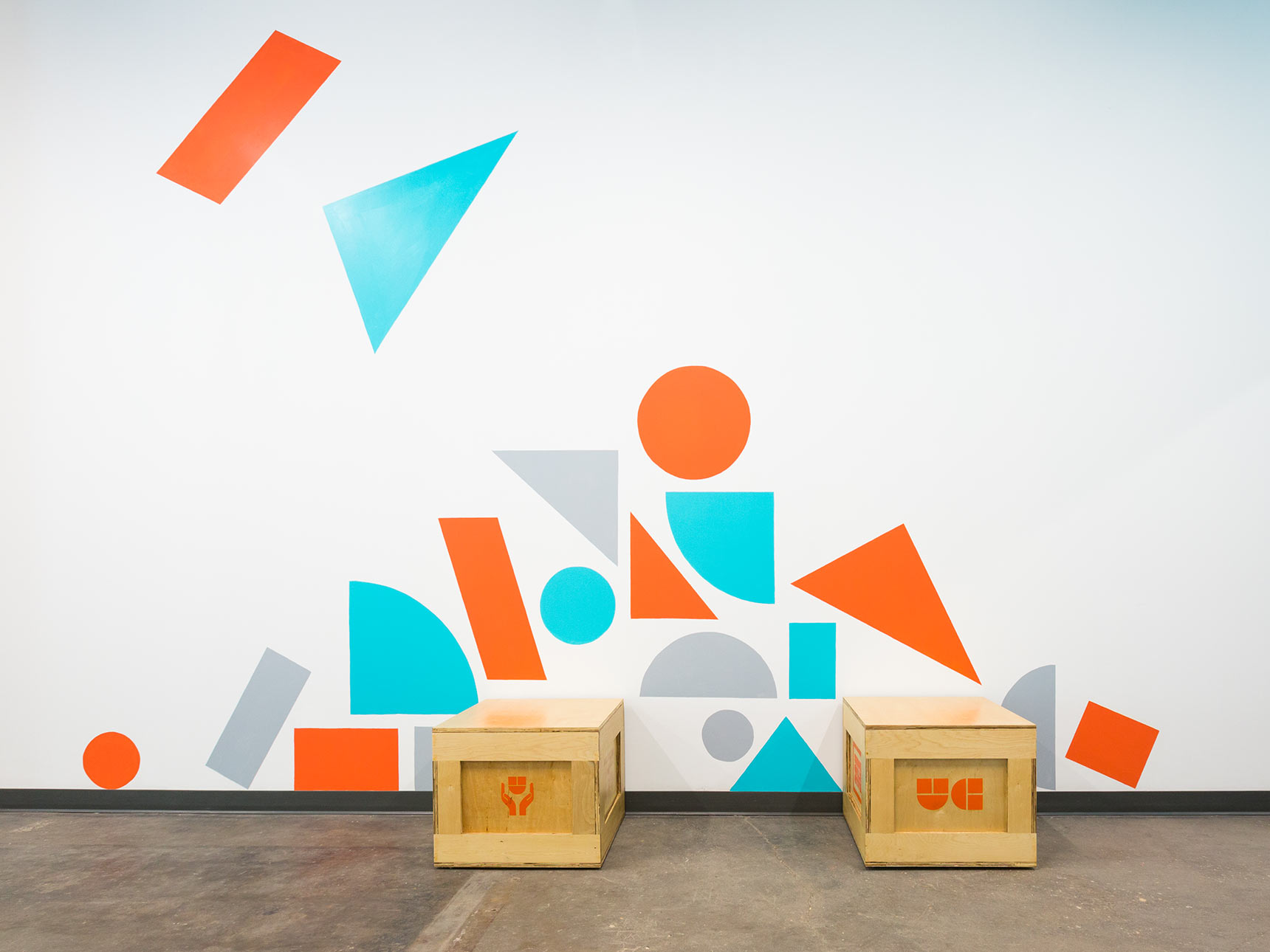 Colorful geometric shape supergraphic murals in the hallways of the Union Collective building, with custom shipping crate seating
