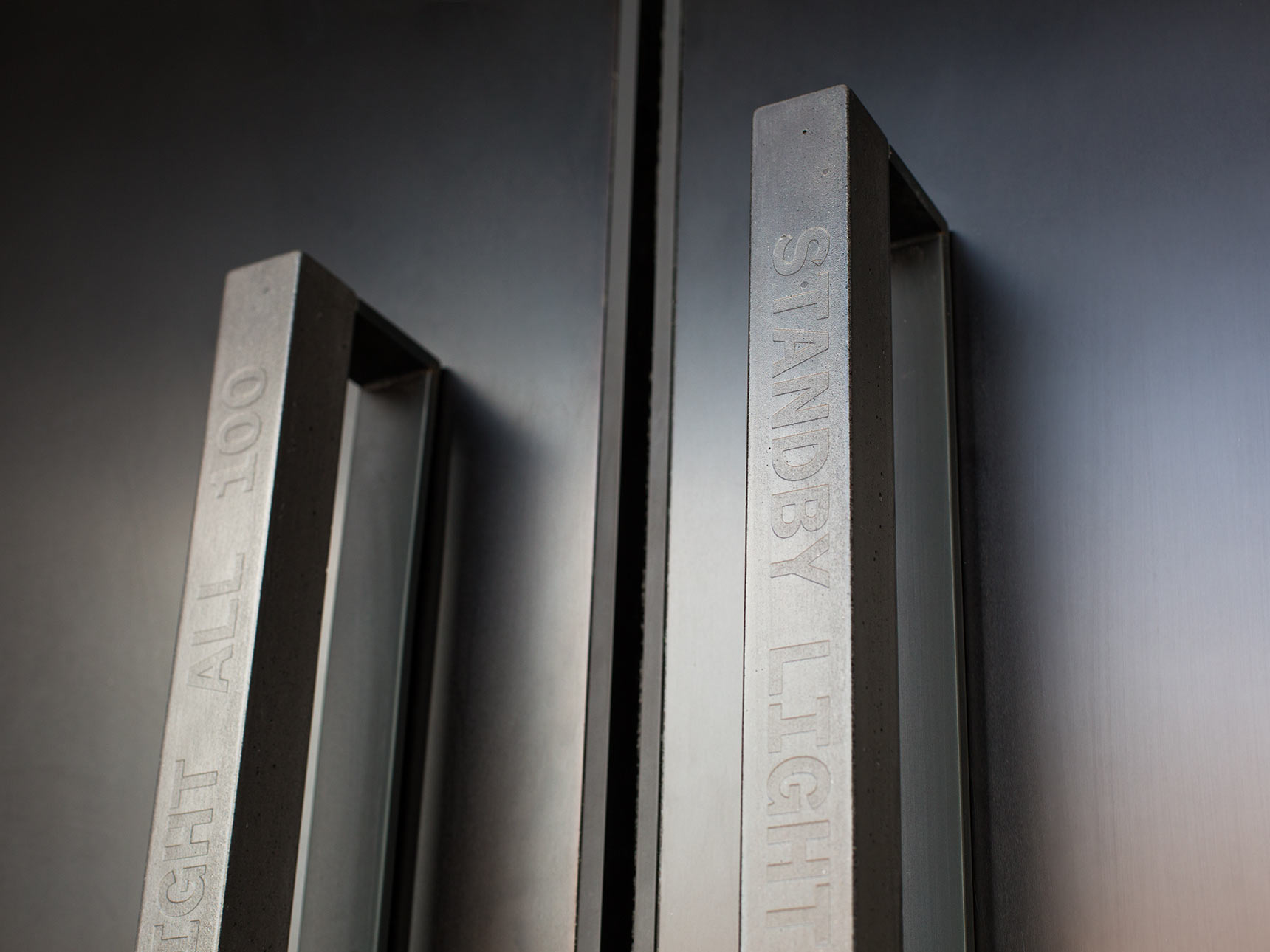 Cast black concrete door pulls with embossed text on the doorways to the Voxel Theater