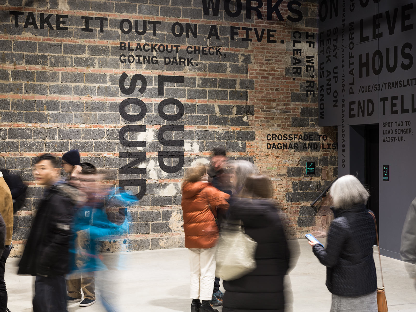 A giant typography kinetic poetry mural of backstage theater cues wraps around the lobby of the Voxel Theater