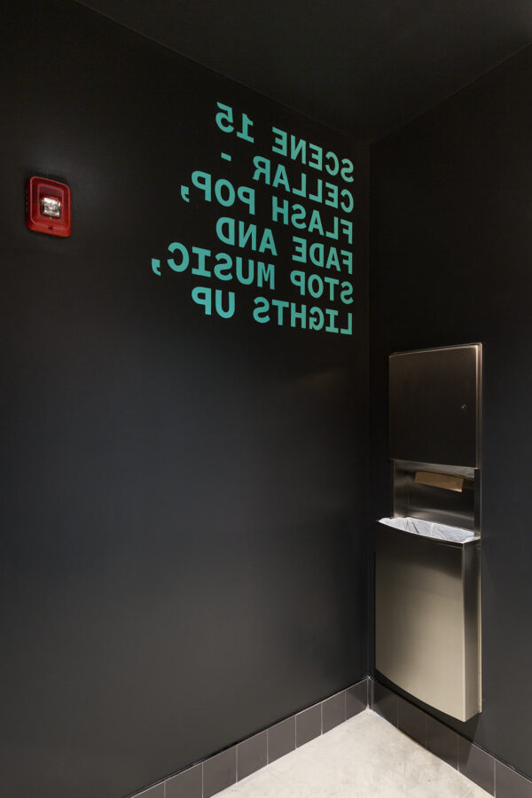 Backwards text and mint-colored giant typography kinetic poetry wraps around the restroom interiors of the Voxel Theater