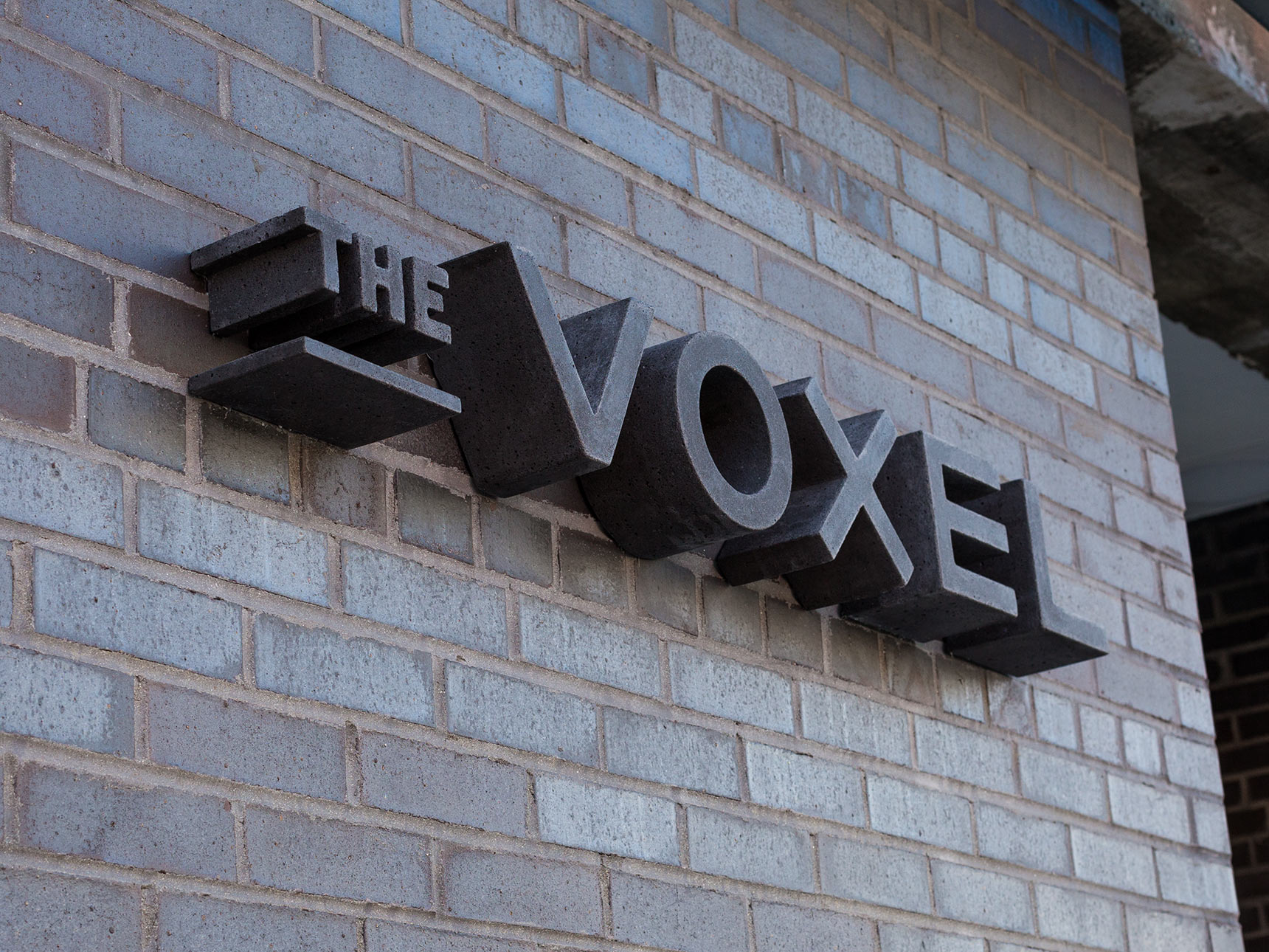 The Voxel, black cast concrete dimensional signage on the a black brick facade